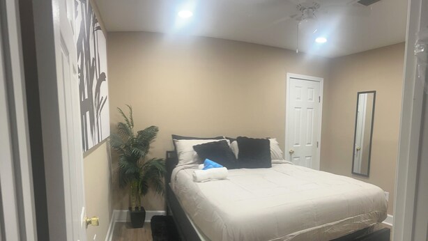 A bedroom with a bed, a potted plant, a door, and a mirror. - 3 Bedroom Home with Long Driveway  & Covered Deck (Jackson)