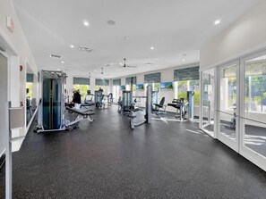 A modern gym with various exercise machines, large windows, and a clean, spacious layout. - Spacious 5-bed /4-bath townhome in lovely Kissimmee w/ private pool (Kissimmee)
