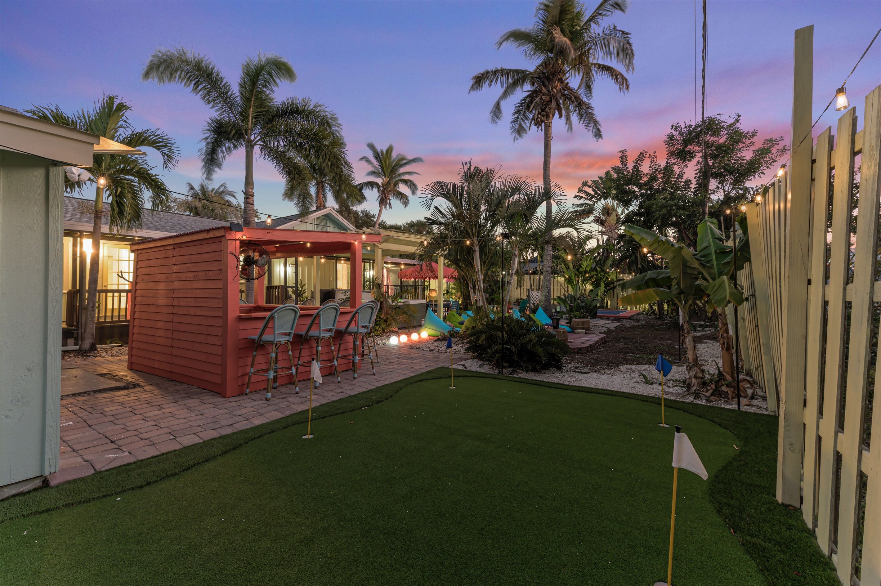 A backyard with a pool table, a red playhouse, and a small patio area.