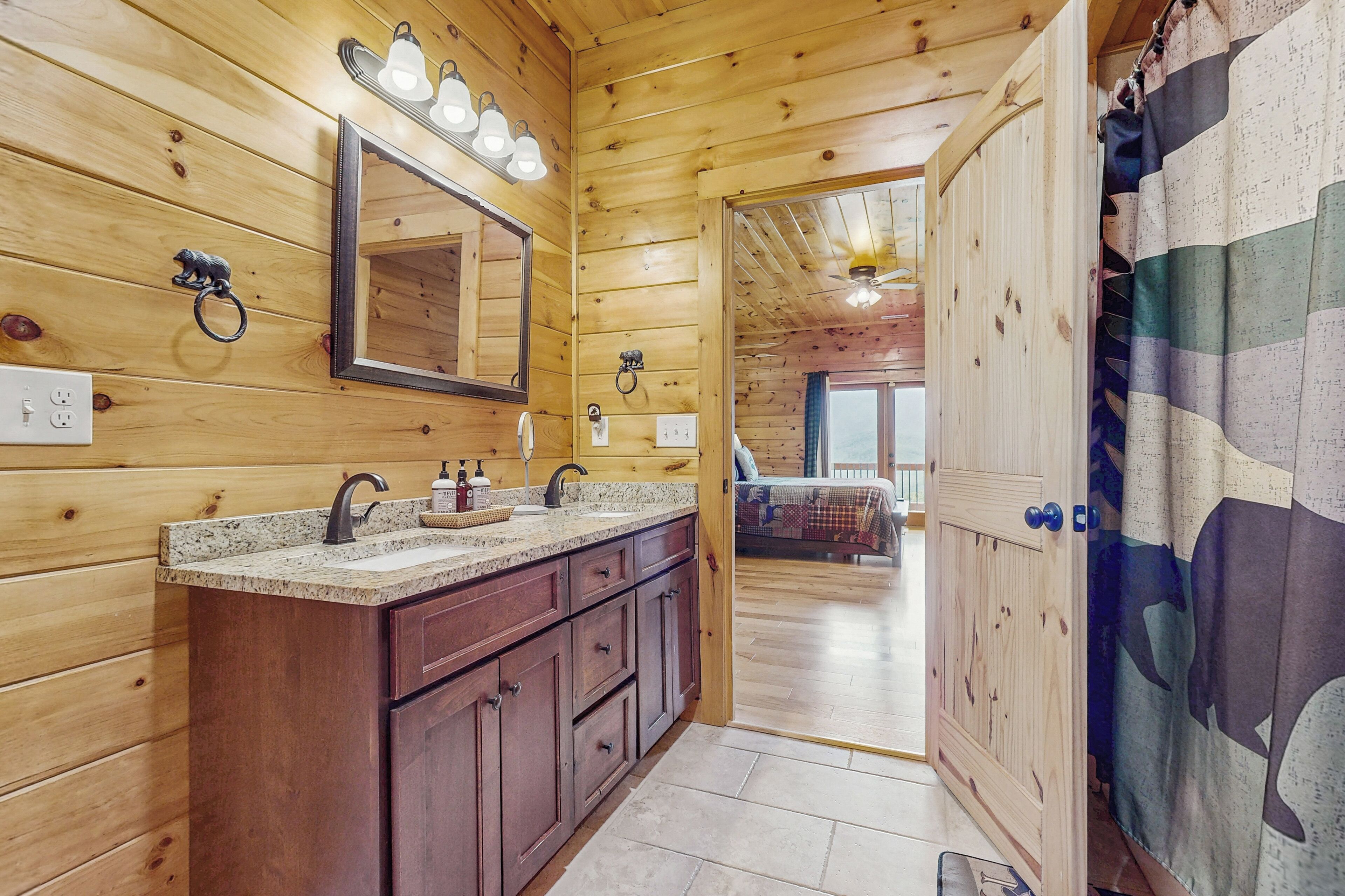 A wooden cabin bathroom with a sink, mirror, and lights.