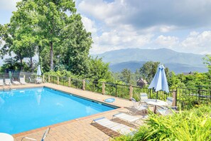 A swimming pool with lounge chairs and umbrellas, surrounded by greenery and mountains in the background. - Theater + Arcade! 'Tri-Star Lodge' in Gatlinburg (Gatlinburg)