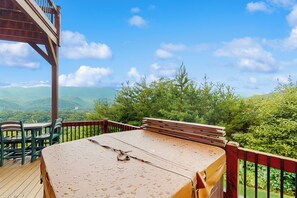 A wooden deck with a bed, chairs, and a view of green hills. - Theater + Arcade! 'Tri-Star Lodge' in Gatlinburg (Gatlinburg)