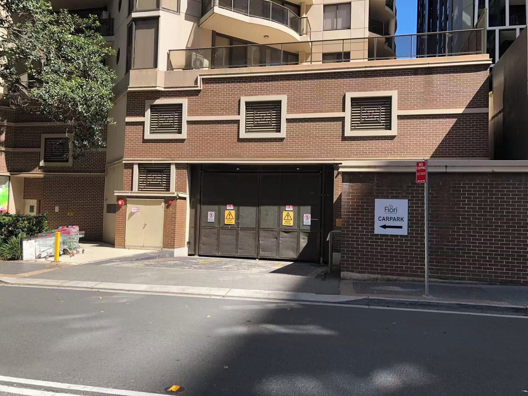 Un edificio in mattoni con un accesso per garage, un segnale di divieto di sosta e l'indicazione di un parcheggio.