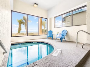 A pool area with a view of palm trees and the ocean, two blue chairs, and a sign indicating the pool's depth. - #3Dreamscapes Oceanfront Oasis (North Myrtle Beach)