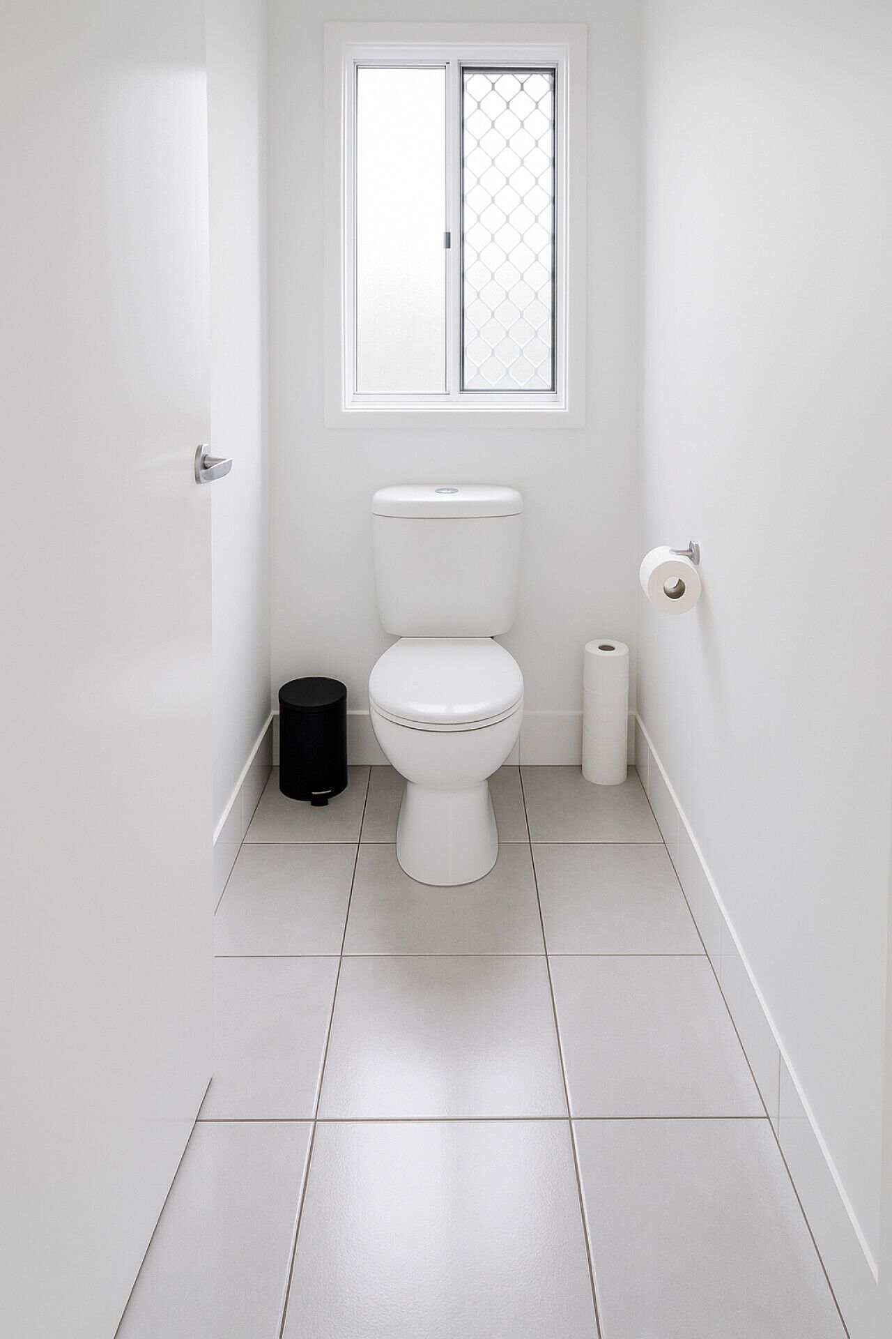 Un bagno piccolo e pulito con il water, un cestino nero e un porta carta igienica.
