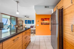 Une cuisine moderne avec des meubles en bois, un réfrigérateur en acier inoxydable et un balcon avec vue.