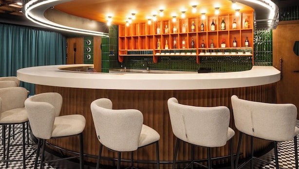 A bar area with a checkered floor, a curved bar counter, and several bar stools.