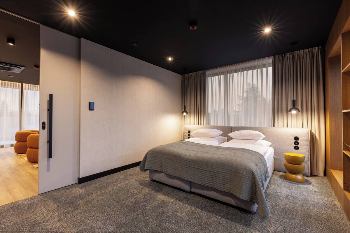 A modern bedroom with a large bed, a wardrobe, and a desk.