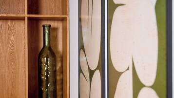 Une étagère en bois sur laquelle sont posés un flacon en verre vert et deux œuvres d’art encadrées destinées à être accrochées au mur.