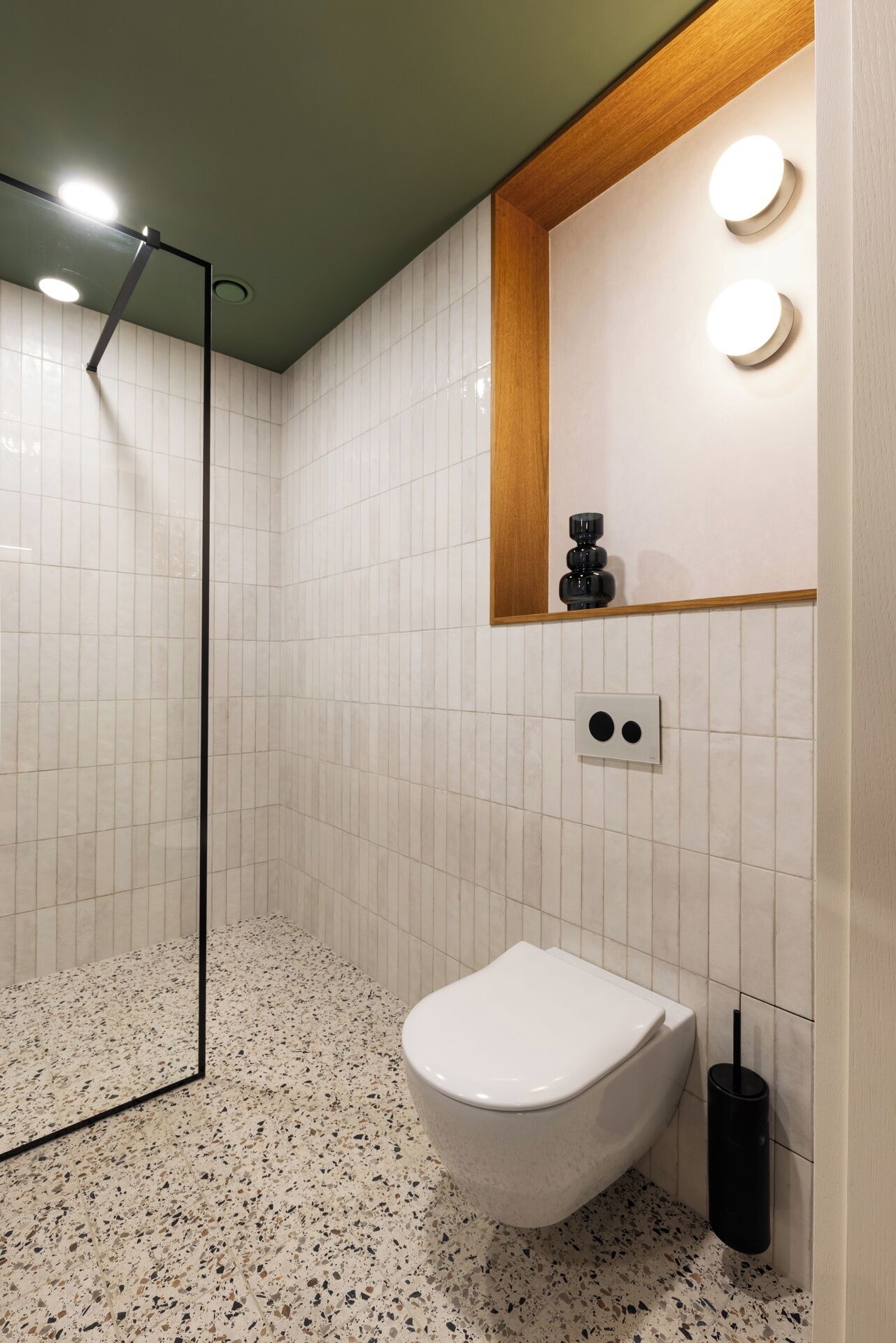 Un bagno con un WC bianco, un bidet nero e uno specchio con cornice in legno.