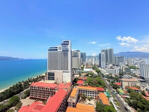 A coastal cityscape with high-rise buildings, a beach, and a clear sky. - Apartment With Balcony (Nha Trang)