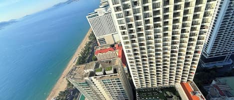 A high-rise building with multiple balconies overlooking a beach and the sea.