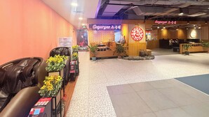 A hotel lobby with a reception desk, seating area, and a wall with a decorative sign. - Apartment With Balcony (Nha Trang)