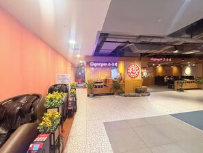 Un hall d’hôtel comprenant un comptoir d’accueil, un espace salon et un mur orné d’une enseigne décorative.