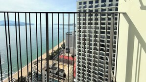 A high-rise building with multiple balconies overlooking a beach and ocean. - Apartment With Balcony (Nha Trang)