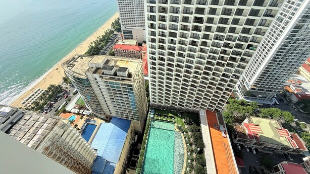 A high-rise hotel with multiple floors, a rooftop pool, and a beach view. - Apartment With Balcony (Nha Trang)