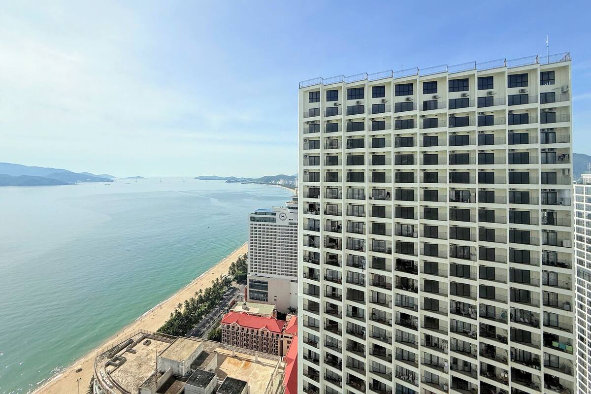 Ein Hochhaus-Hotel mit mehreren Etagen, Balkonen und Blick auf Strand und Meer.