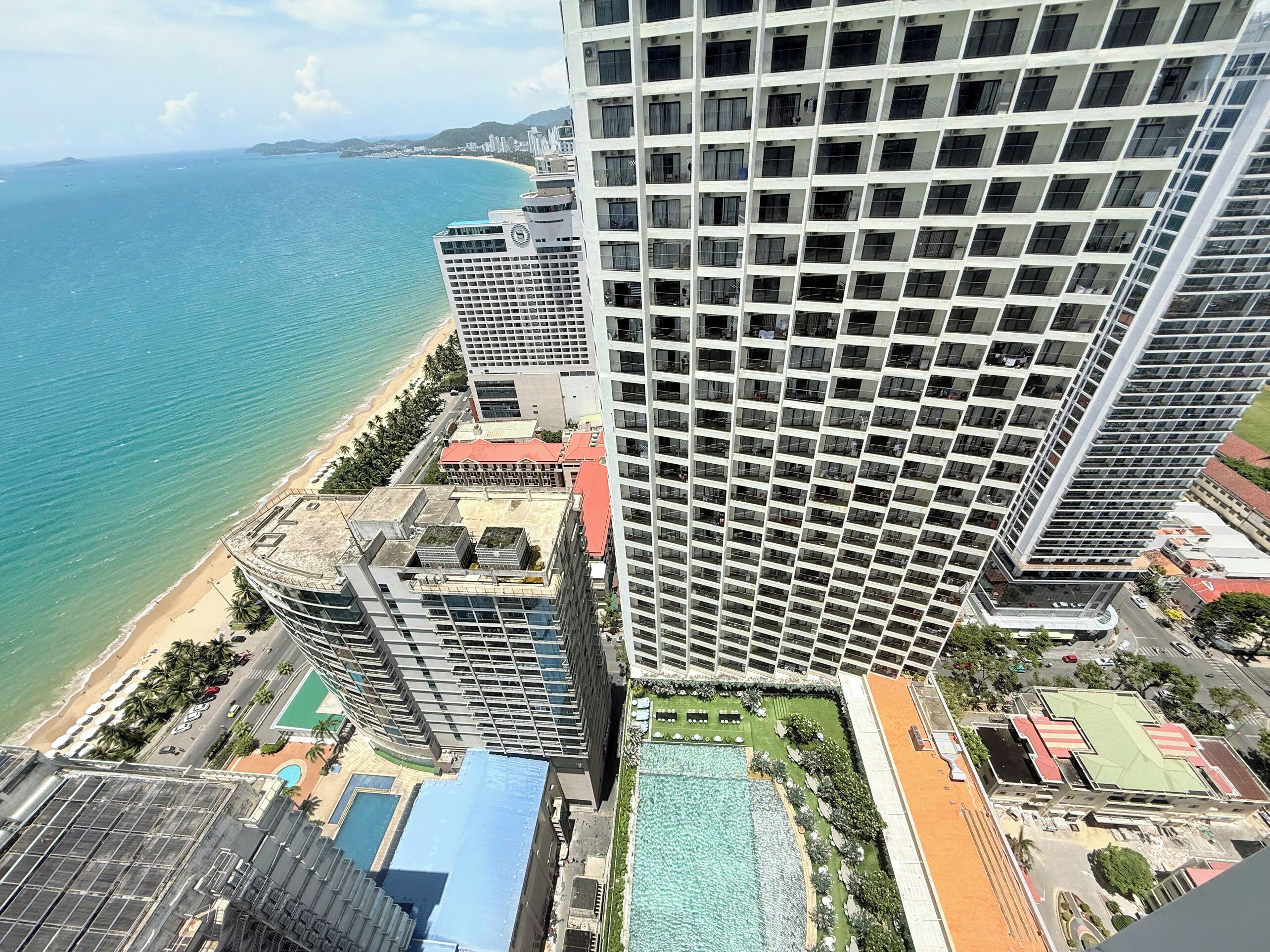 A high-rise hotel with multiple balconies overlooking a beach and the ocean.