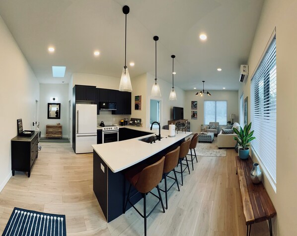 A modern kitchen with a central island, bar stools, and pendant lighting.