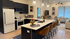 A modern kitchen with dark cabinets, a white refrigerator, a stove, and a central island with bar stools. - Tranquil 1 bedroom in-law suite - walking distance to downtown Delafield (Delafield)