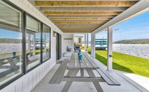 A covered outdoor area with a view of a lake, picnic tables, and a boat dock. - The Pentwater Porch (Pentwater)