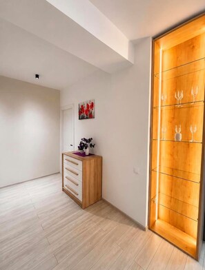 Une pièce comprenant un meuble en bois, une œuvre d’art accrochée au mur et un autre meuble en bois contenant des verres à vin.