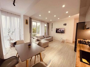 Un salon moderne avec un canapé, une table à manger et un téléviseur fixé au mur.