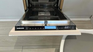 Eine Samsung Spülmaschine mit Bedienfeld, unter einer Holzausziehtischplatte.