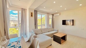 Uma sala de estar moderna com um sofá, uma mesa de centro e uma TV fixada na parede.