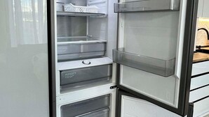 Ein moderner, leerer Kühlschrank mit mehreren Ablagen und Schubladen, der viel Stauraum bietet.