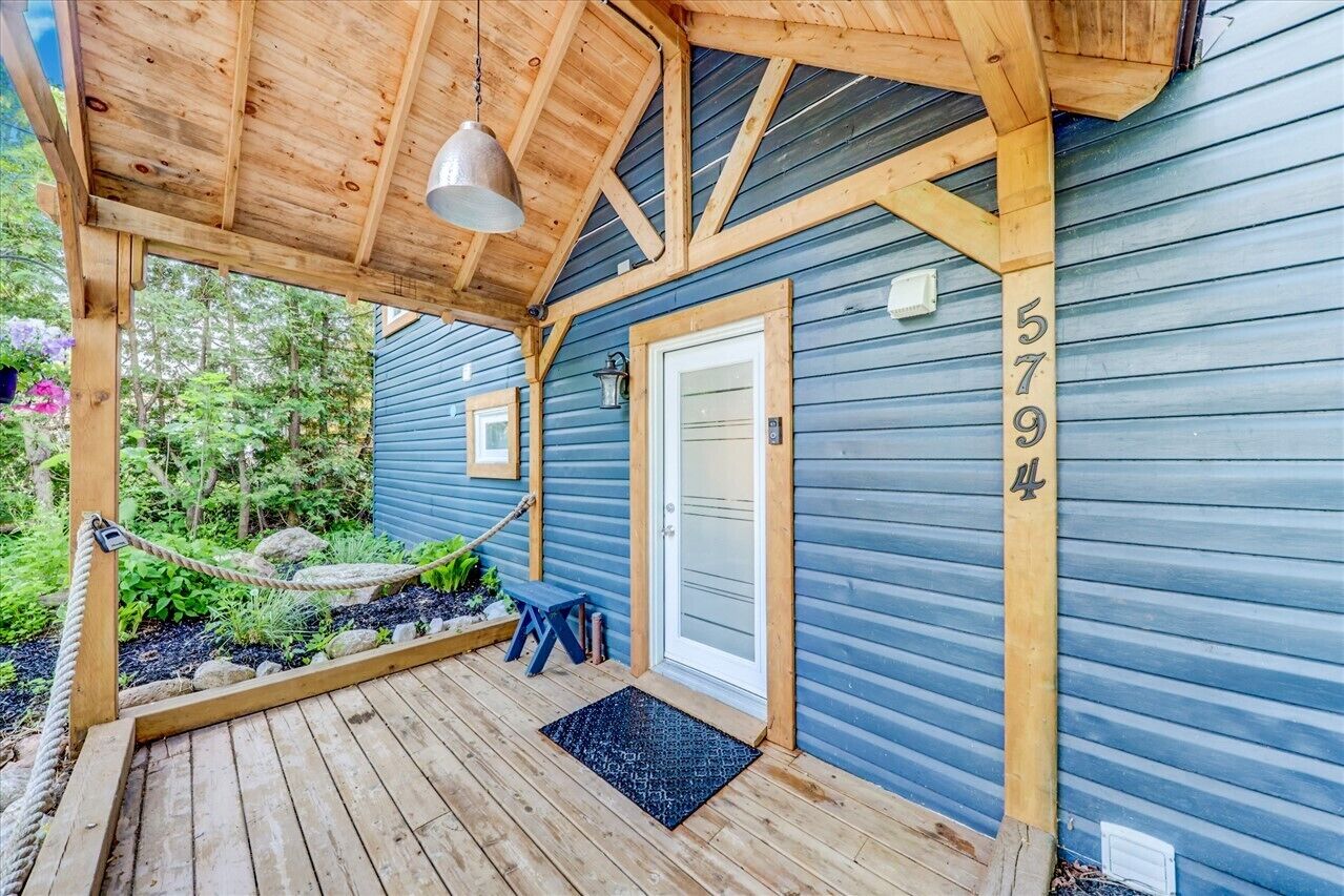 A wooden deck with a hanging light fixture, a door, and a mailbox.