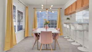 A dining area with a white table, pink chairs, and a modern chandelier. - Modern Luxury Home near Denver (Westminster)