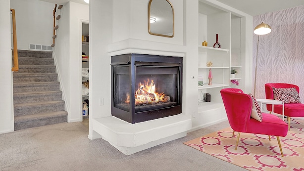 A living room with a fireplace, a staircase, and a red chair. - Modern Luxury Home near Denver (Westminster)