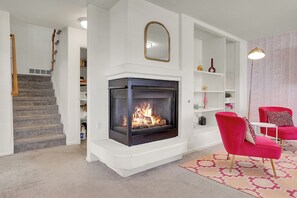 A living room with a fireplace, a staircase, and a red chair. - Modern Luxury Home near Denver (Westminster)