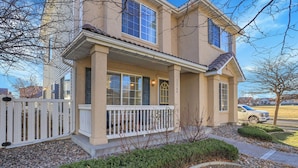 A two-story house with a porch, a picket fence, and a driveway. - Modern Luxury Home near Denver (Westminster)