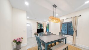 Een eethoek met een houten tafel, stoelen en een bank. Daarboven hangt een lamp.