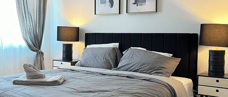 A modern bedroom with a large bed, two bedside tables, and a nightstand.