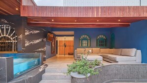 Uma área interna de piscina moderna com hidromassagem, um sofá e uma escadaria que leva a uma entrada coberta.