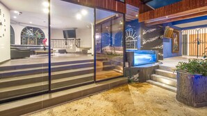 Uma casa moderna com uma ampla porta de correr de vidro que dá para uma sala de estar com televisão, assentos e escada.