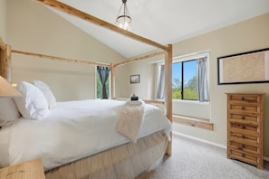 Un dormitorio con una cama con dosel, un aparador de madera y un mapa en la pared.