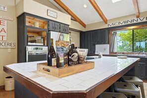 A kitchen with a large island, dark cabinetry, and a window with a view of trees.
