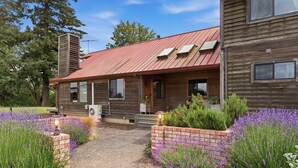 A wooden house with a red roof, a brick pathway, and lavender plants. - Spacious Farm Stay featuring Petey the Donkey (McMinnville)