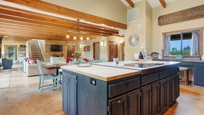 A spacious kitchen with a large island, wooden beams, and a dining area with a staircase. - Spacious Farm Stay featuring Petey the Donkey (McMinnville)