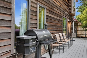 Une terrasse en bois avec un barbecue et des siĂšges dâextĂ©rieur.