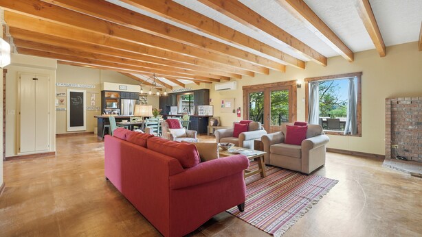 A spacious living area with a wooden ceiling, a red sofa, beige armchairs, and a kitchen in the background. - Spacious Farm Stay featuring Petey the Donkey (McMinnville)