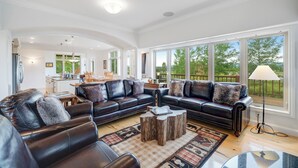 A spacious living room with a sectional sofa, a coffee table, and large windows offering a view of the outdoors.