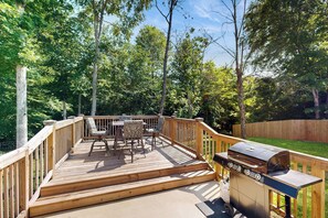 A wooden deck with outdoor furniture and a grill.
