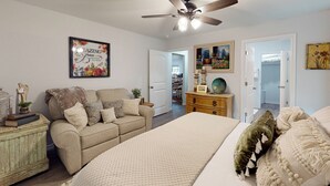 Ein Schlafzimmer mit Bett, Sofa, Kommode und Deckenventilator.