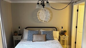 A neatly made bed with a blue and white bedspread, a decorative wall hanging, and a black metal headboard. - "5 Mins Driving Distance from The Ark Encounter & Creation Museum" (Williamstown)