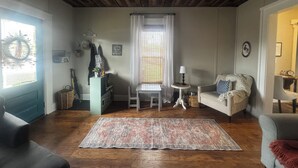 A cozy living room with a wooden ceiling, a patterned rug, a white chair, a sofa, and a small table with a lamp. - "5 Mins Driving Distance from The Ark Encounter & Creation Museum" (Williamstown)